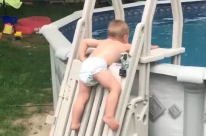 Niño de 2 años trepa por las escaleras de seguridad de una piscina