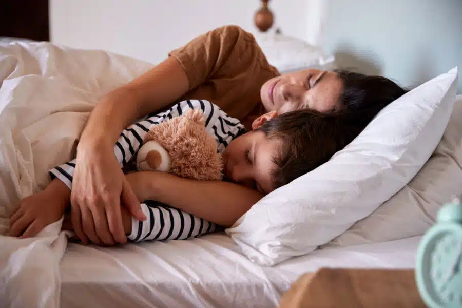 Hijo durmiendo en la cama de su madre